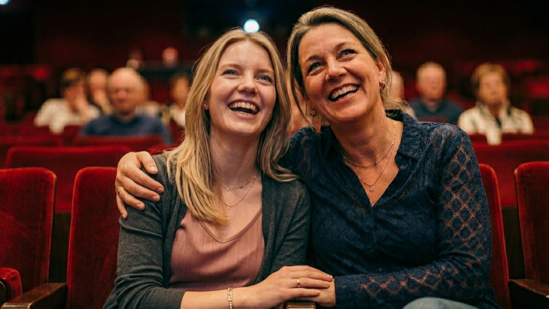 Sfeerbeeld van moeder en dochter in theaterzaal met rode stoelen